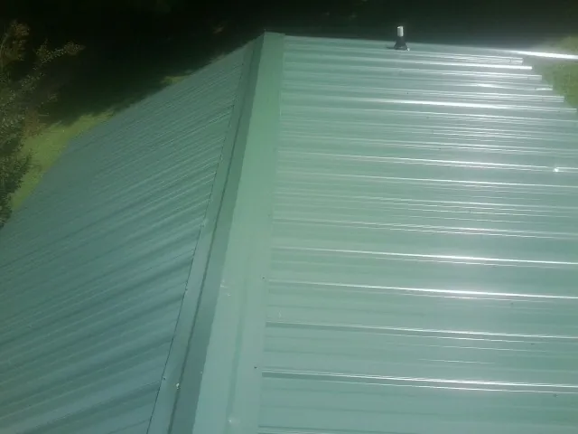 New green metal panels meeting at the ridge of a roof — Flat Roof Repair work by our crew in Wildwood