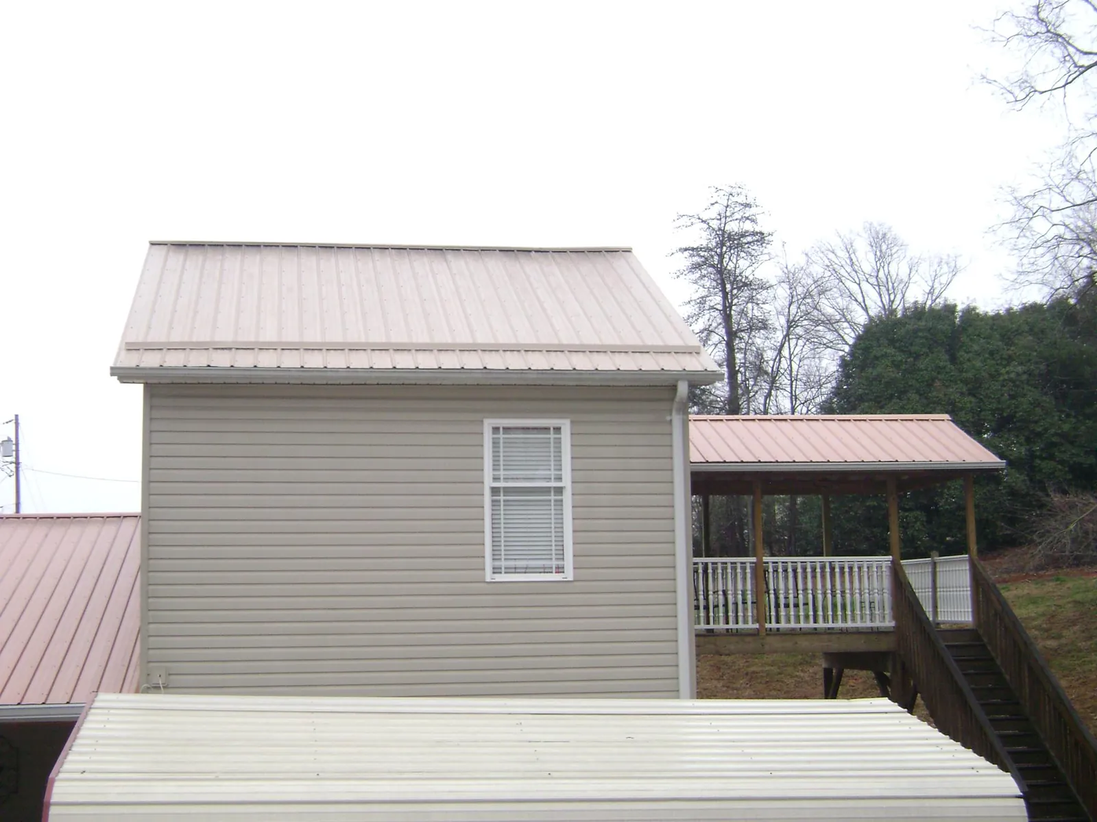 Tan metal roofs on a two story addition and attached porch, from a Roof Replacement job in Wildwood